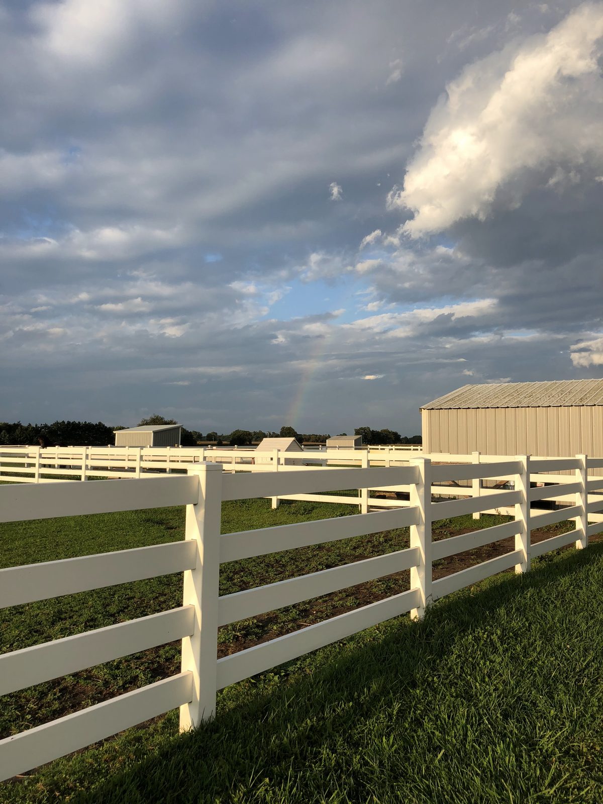 Lone Tree Stables white fencing and rainbow